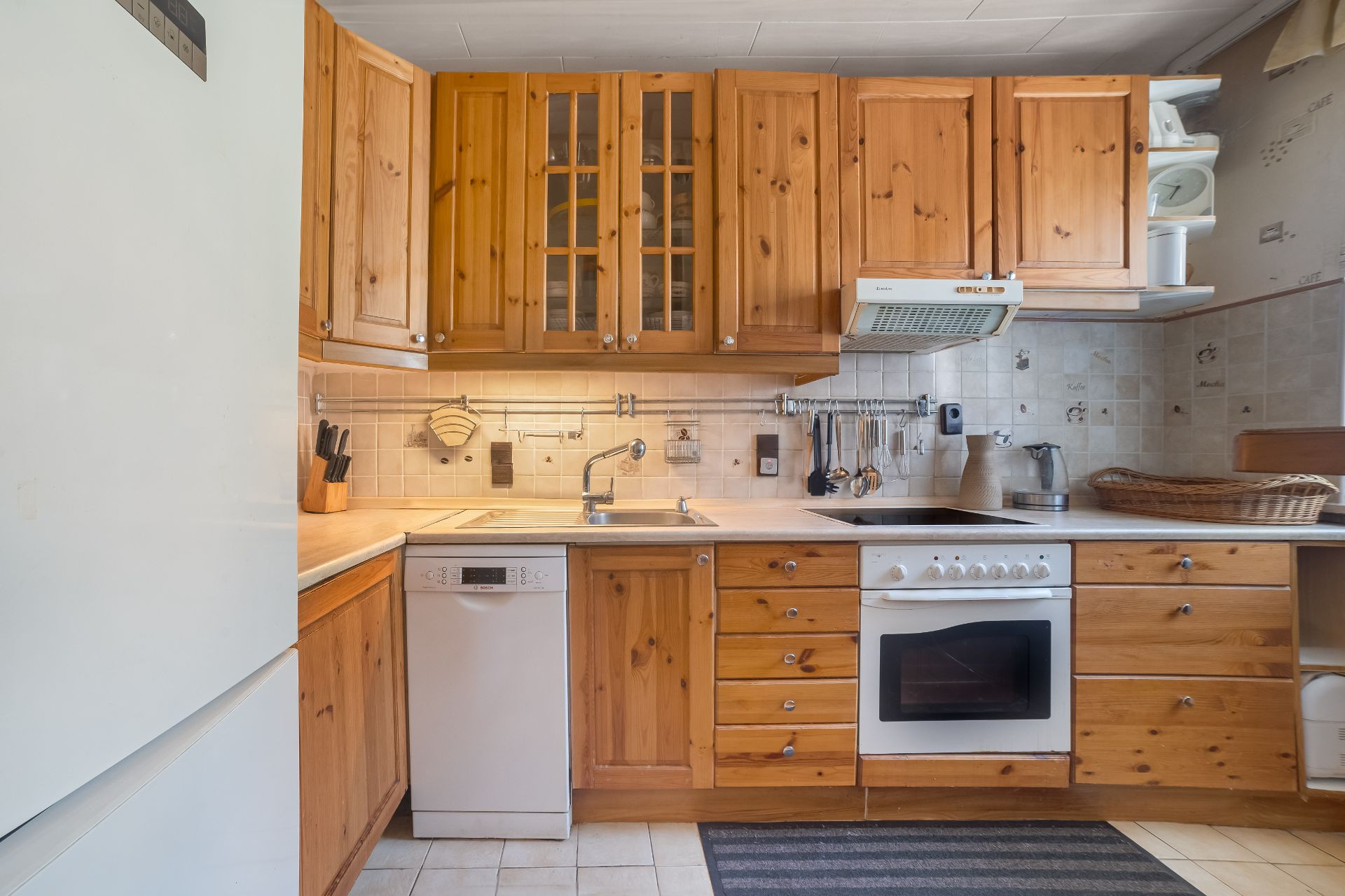 Küche mit Holzmöbeln, Einbauherd, Spülmaschine und Hängeschränken.