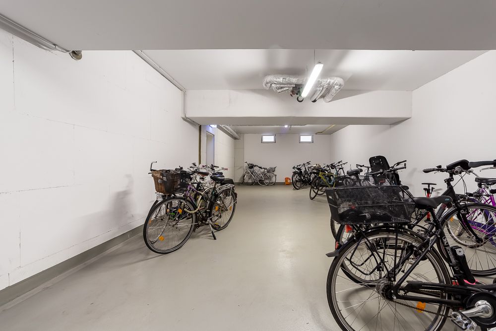 Heller Fahrradraum mit mehreren abgestellten Fahrrädern an den Wänden.