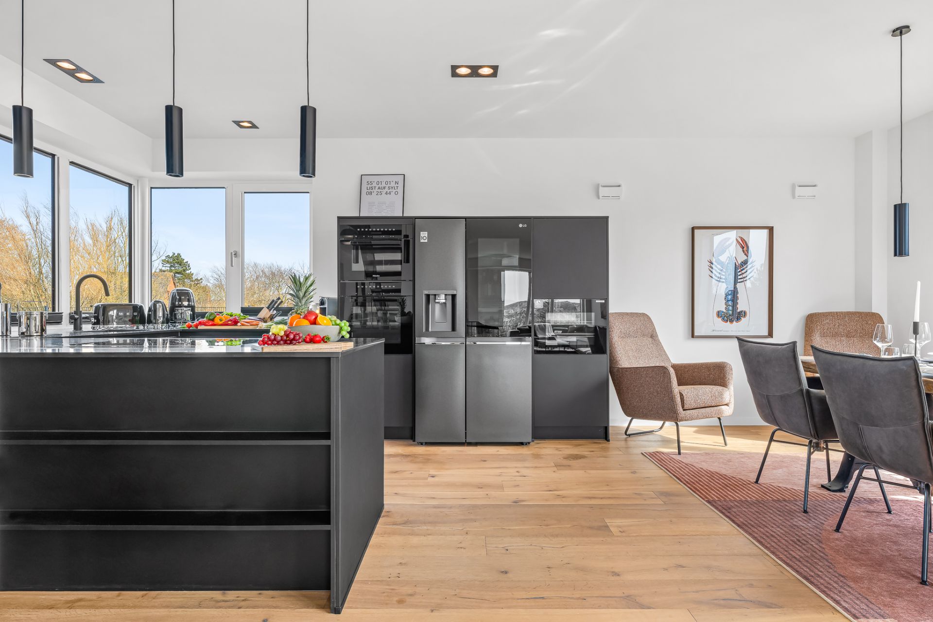Moderne offene Küche mit Insel, schwarzem Kühlschrank und Essbereich auf Holzfußboden.