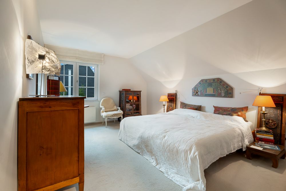 Helles Schlafzimmer mit großem Bett, Nachttischen, Sessel und Fenster.