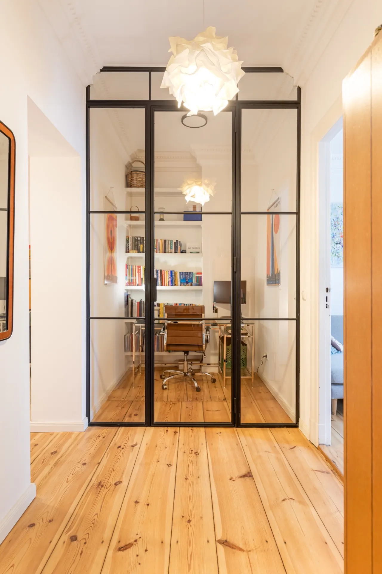 Flur mit Glastüren, dahinter ein Arbeitszimmer mit Bücherregalen und Schreibtisch.