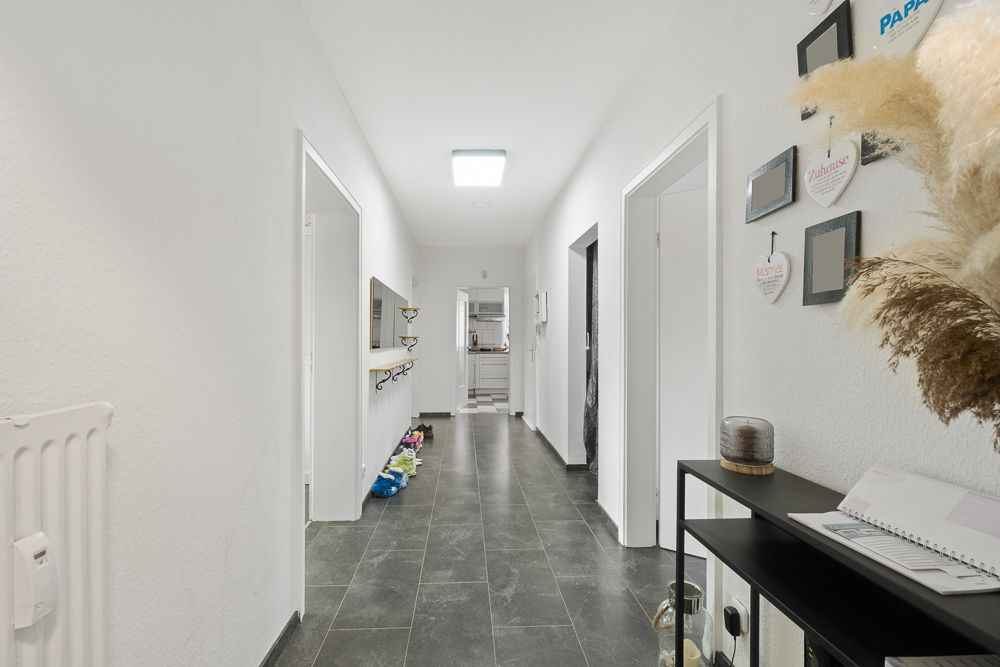 Heller Flur mit mehreren Türen, Dekoration an der Wand und Konsole mit Spiegel.
