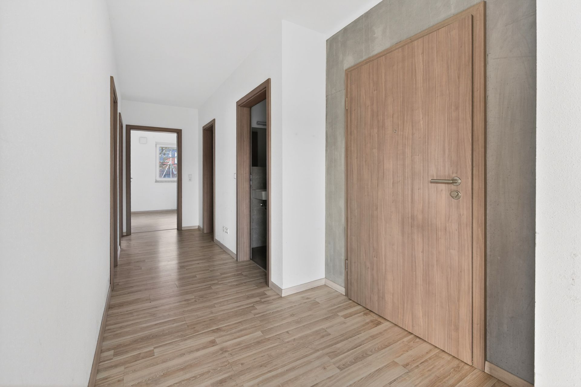 Heller Flur mit Holzboden, mehreren Türen und weiß gestrichenen Wänden.