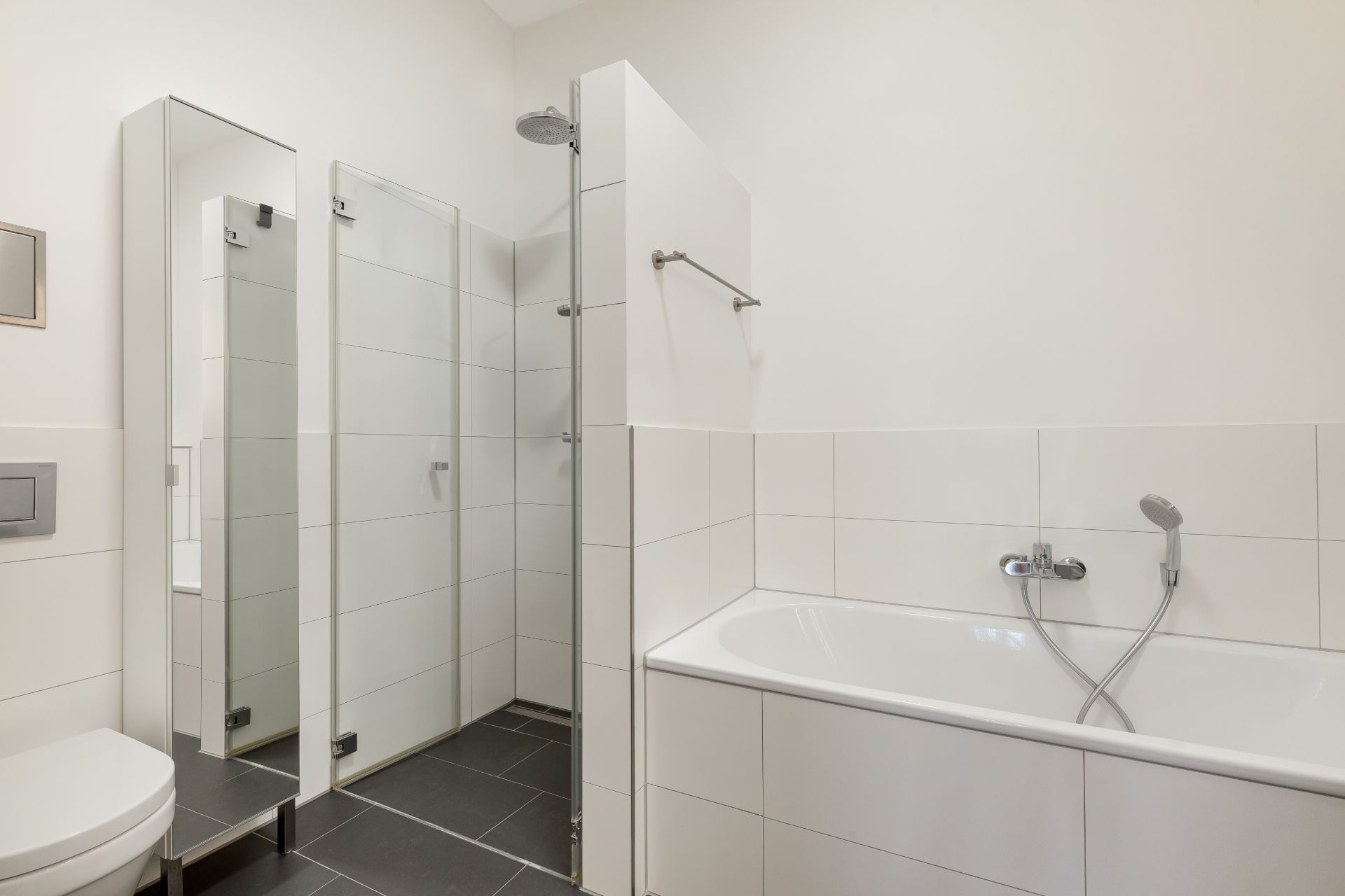 Modernes Badezimmer mit Badewanne, Dusche, WC und großem Spiegel.