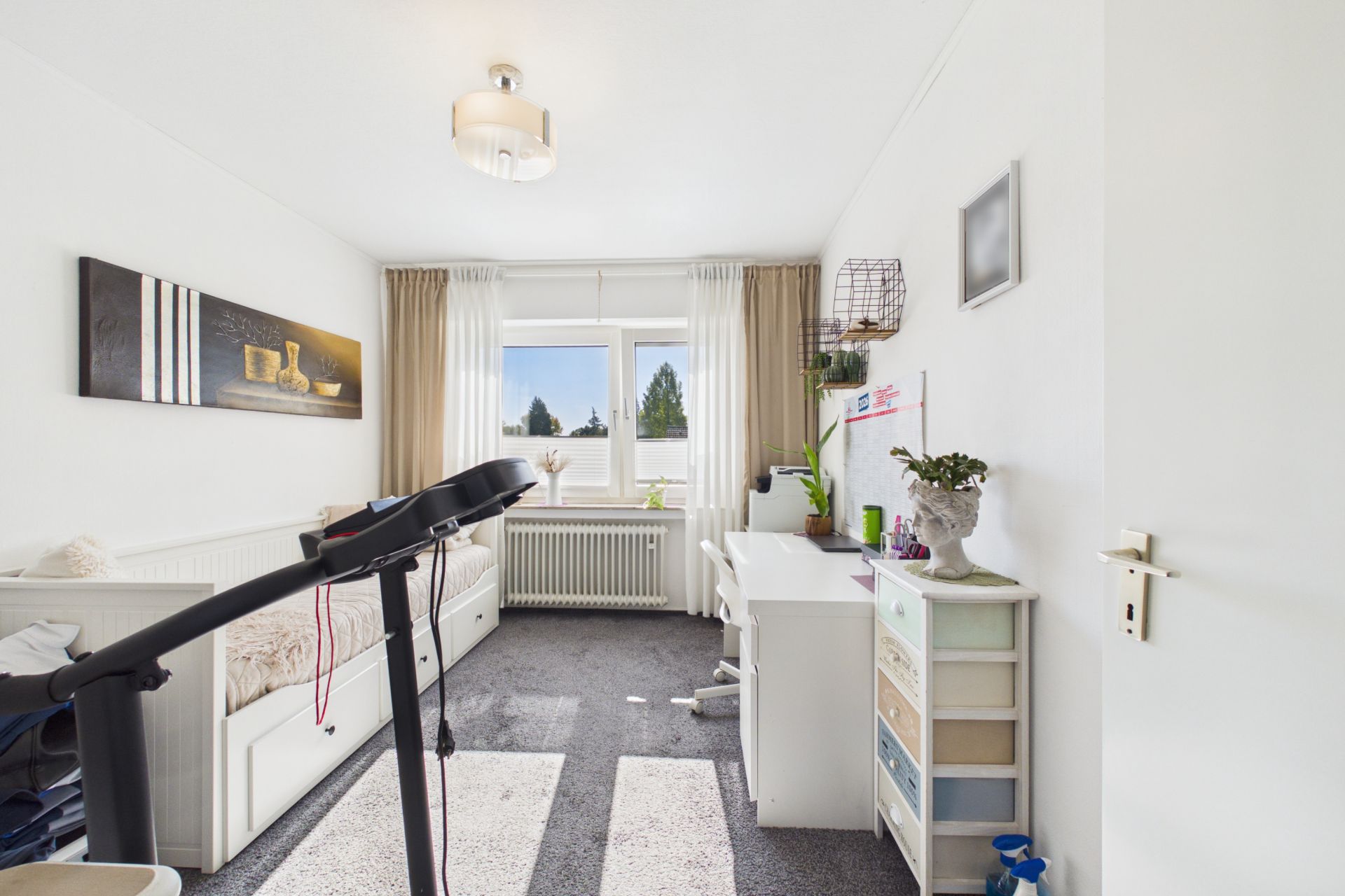 Helles Zimmer mit Bett, Schreibtisch, Fenster, Pflanzen und Laufband.