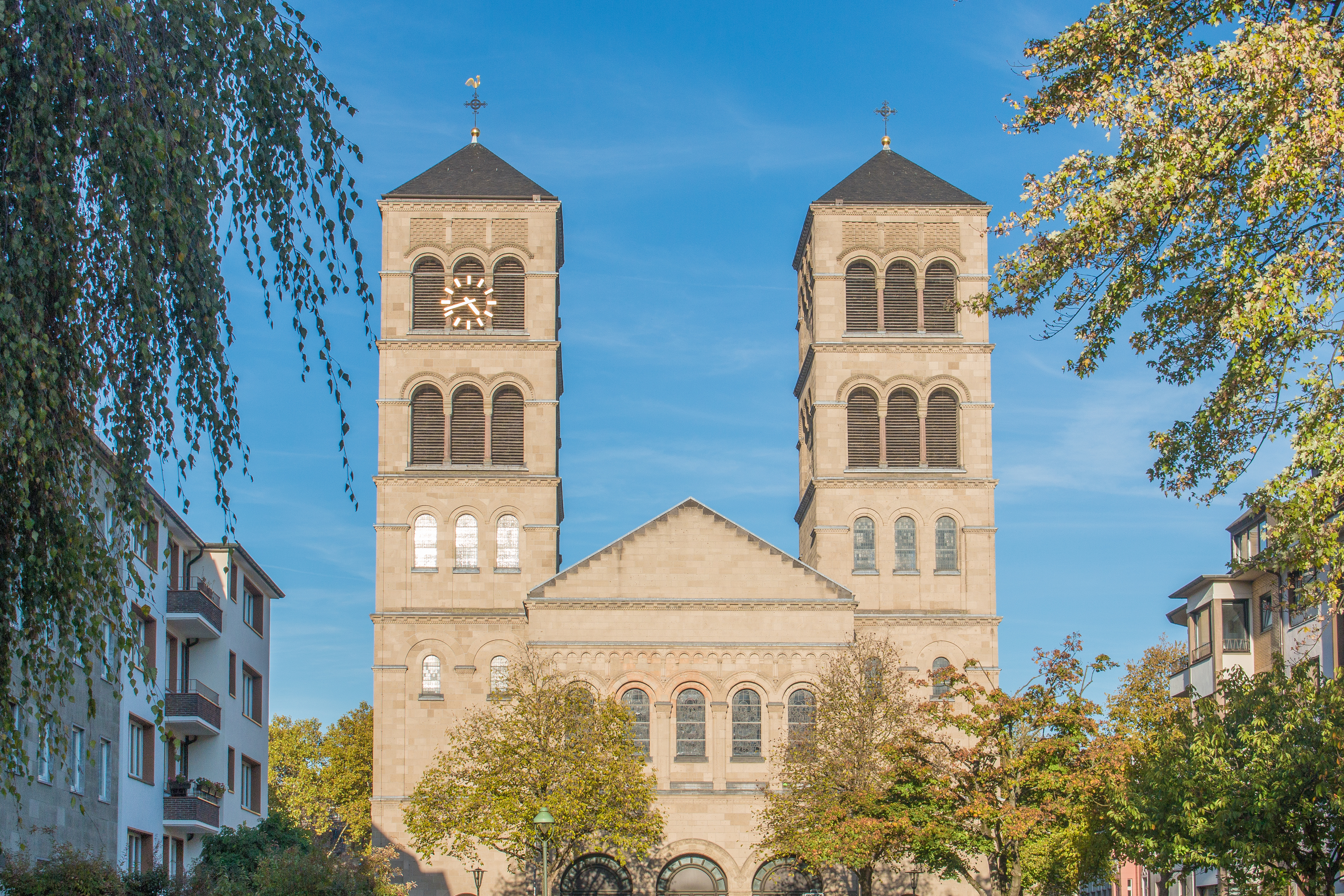 Historisches Gebäude mit Uhrturm und Reiterstatue auf einem offenen Platz, umgeben von Wohnhäusern.