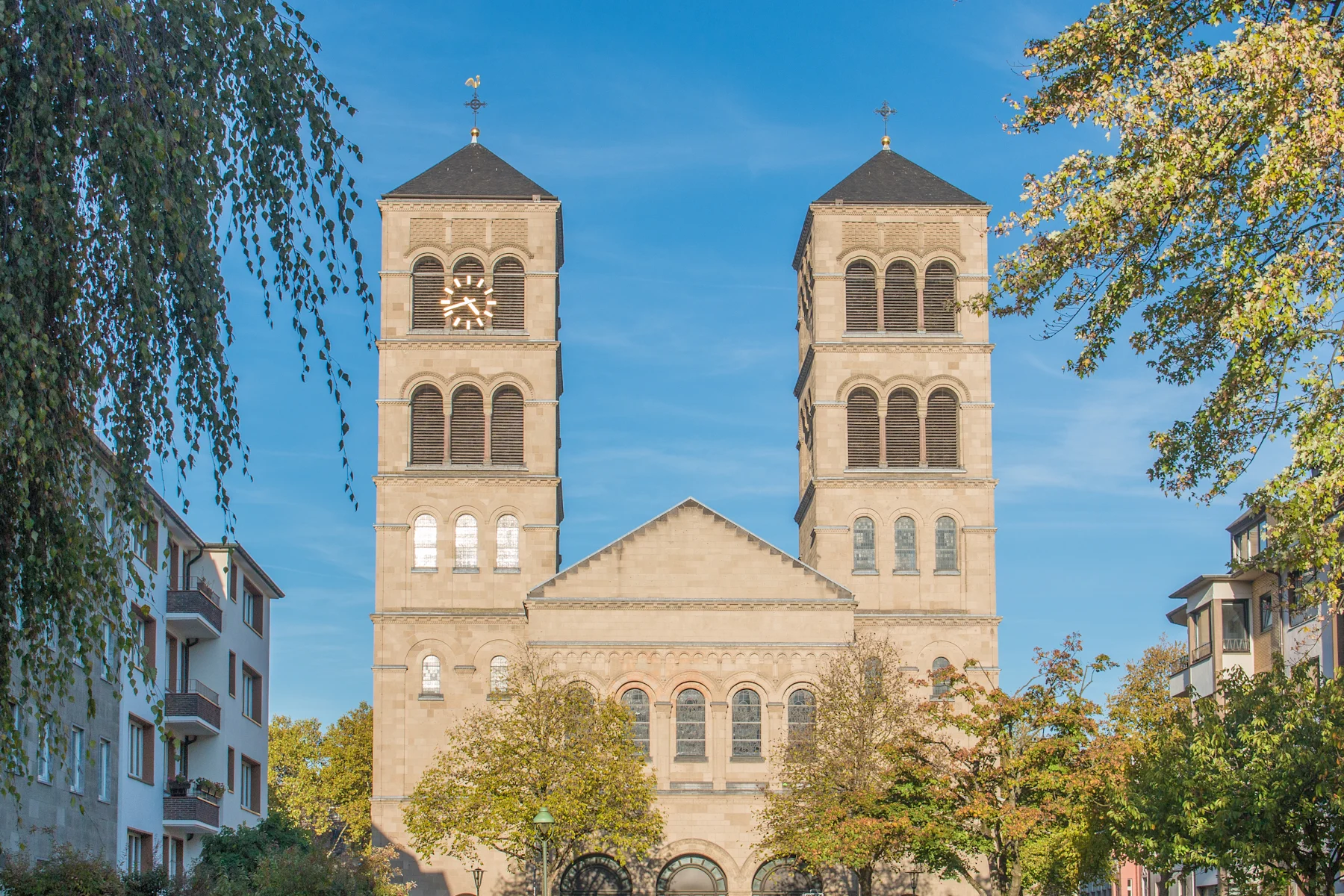 Historisches Gebäude mit Uhrturm und Reiterstatue auf einem offenen Platz, umgeben von Wohnhäusern.