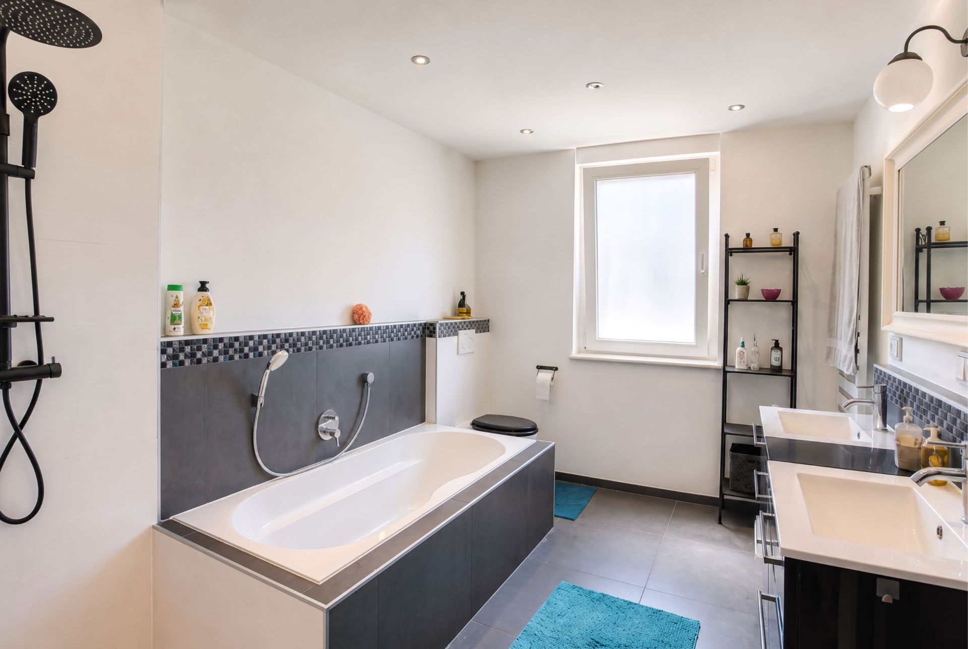Modernes Badezimmer mit Badewanne, Doppelwaschbecken, Regendusche und einem Fenster.