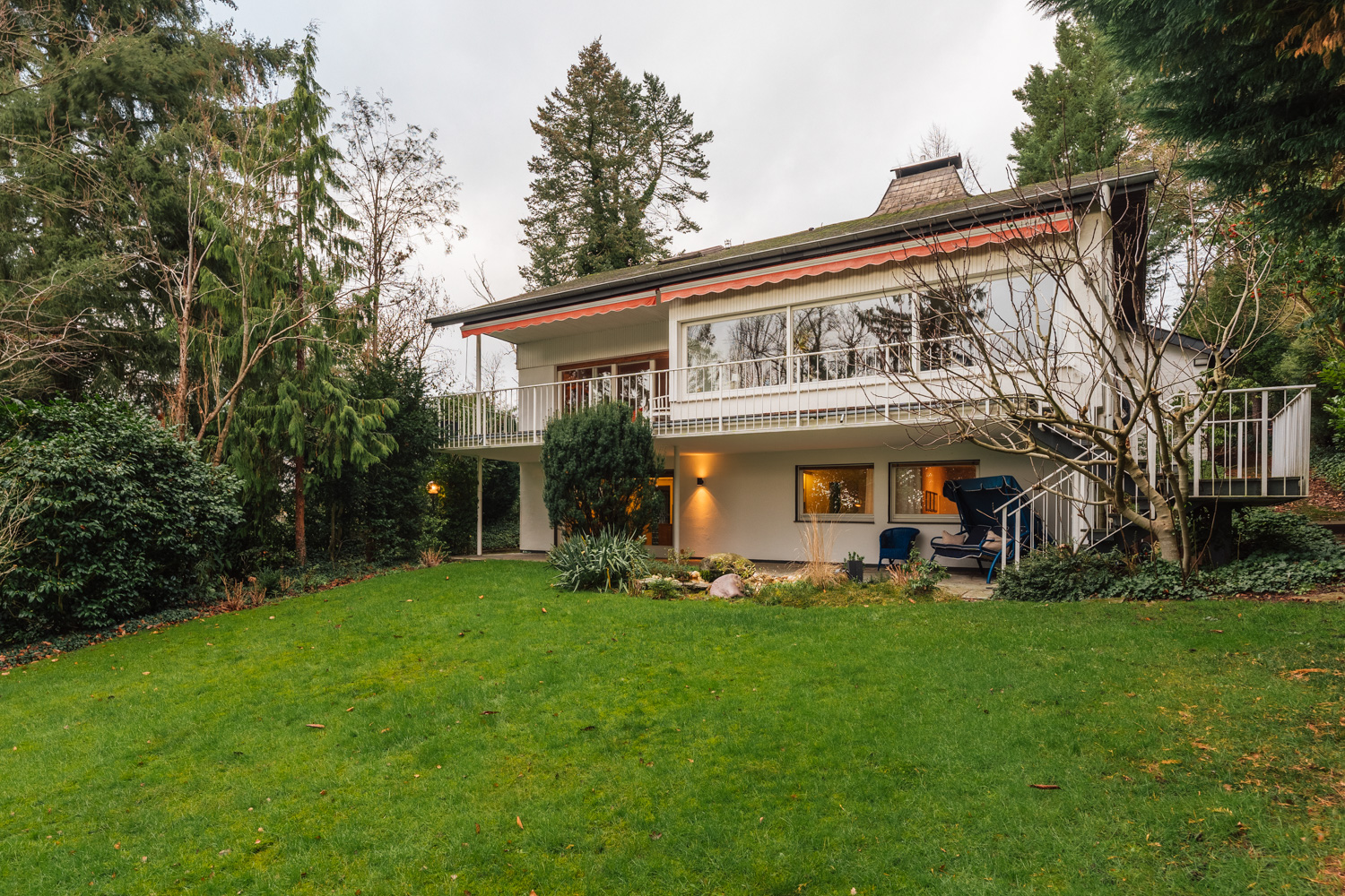 Zweistöckiges Wohnhaus mit großem Garten, Terrasse und umliegenden Bäumen.