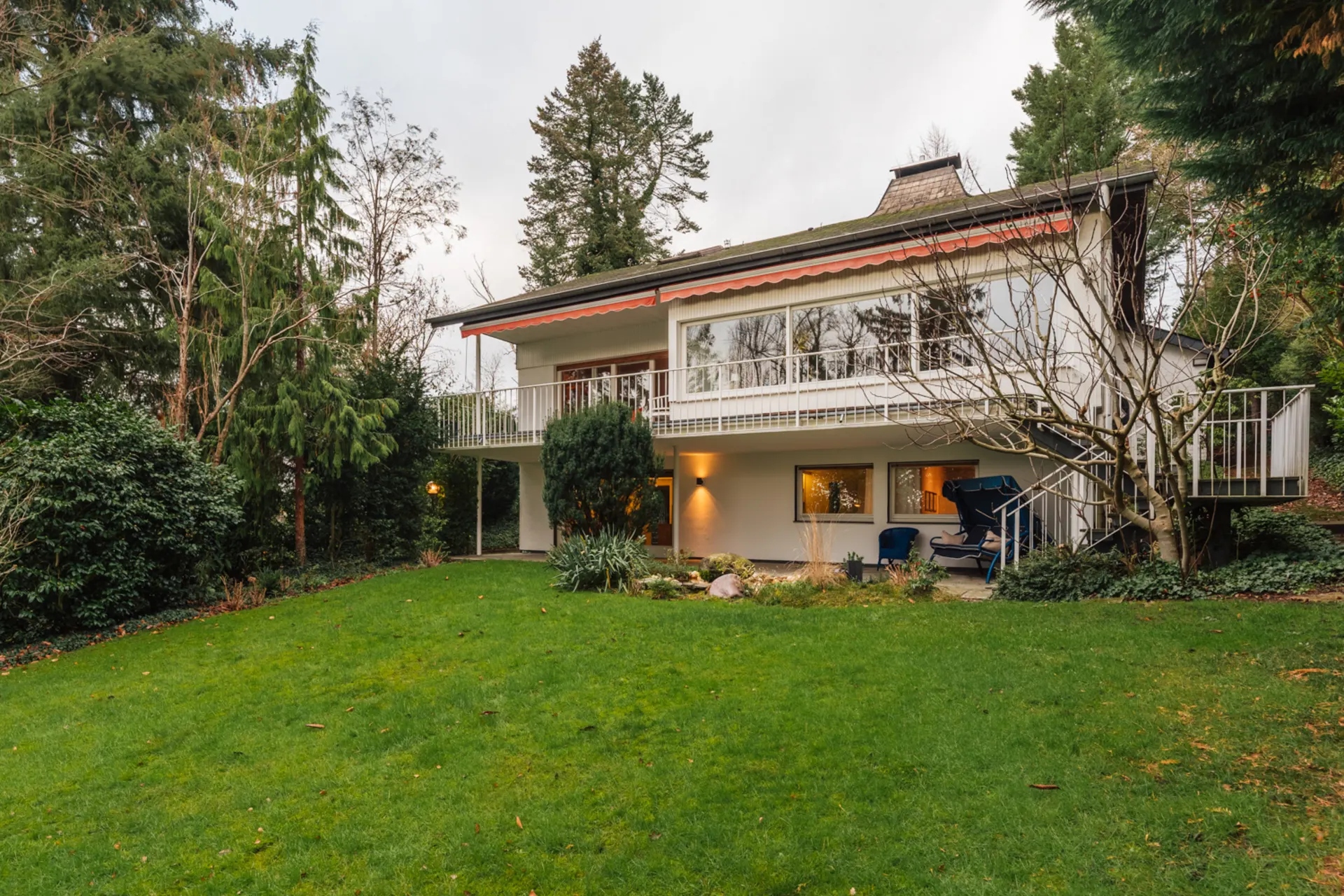 Zweistöckiges Wohnhaus mit großem Garten, Terrasse und umliegenden Bäumen.