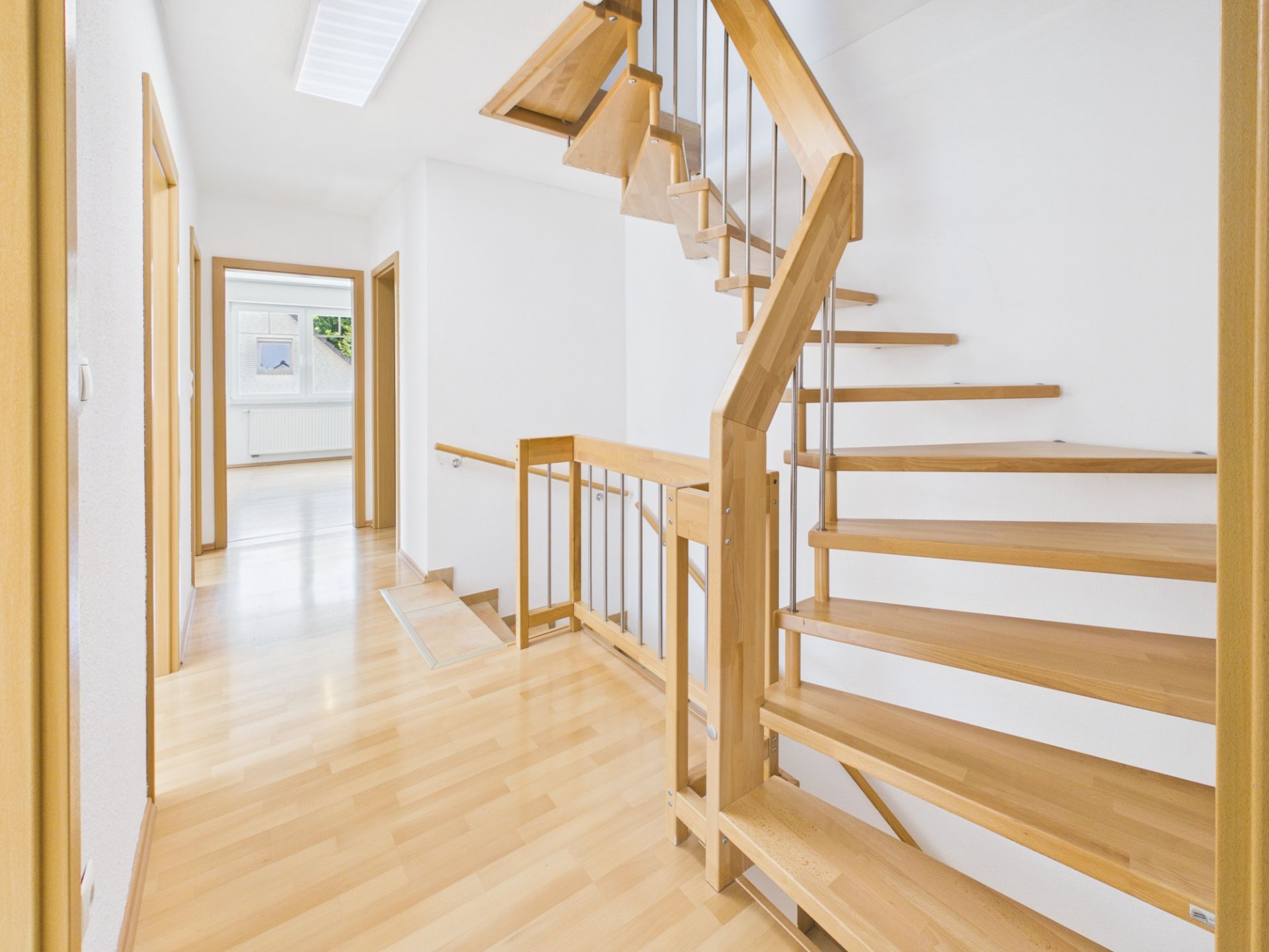 Heller Flur mit Holztreppe und mehreren Türen in einem Wohnhaus.