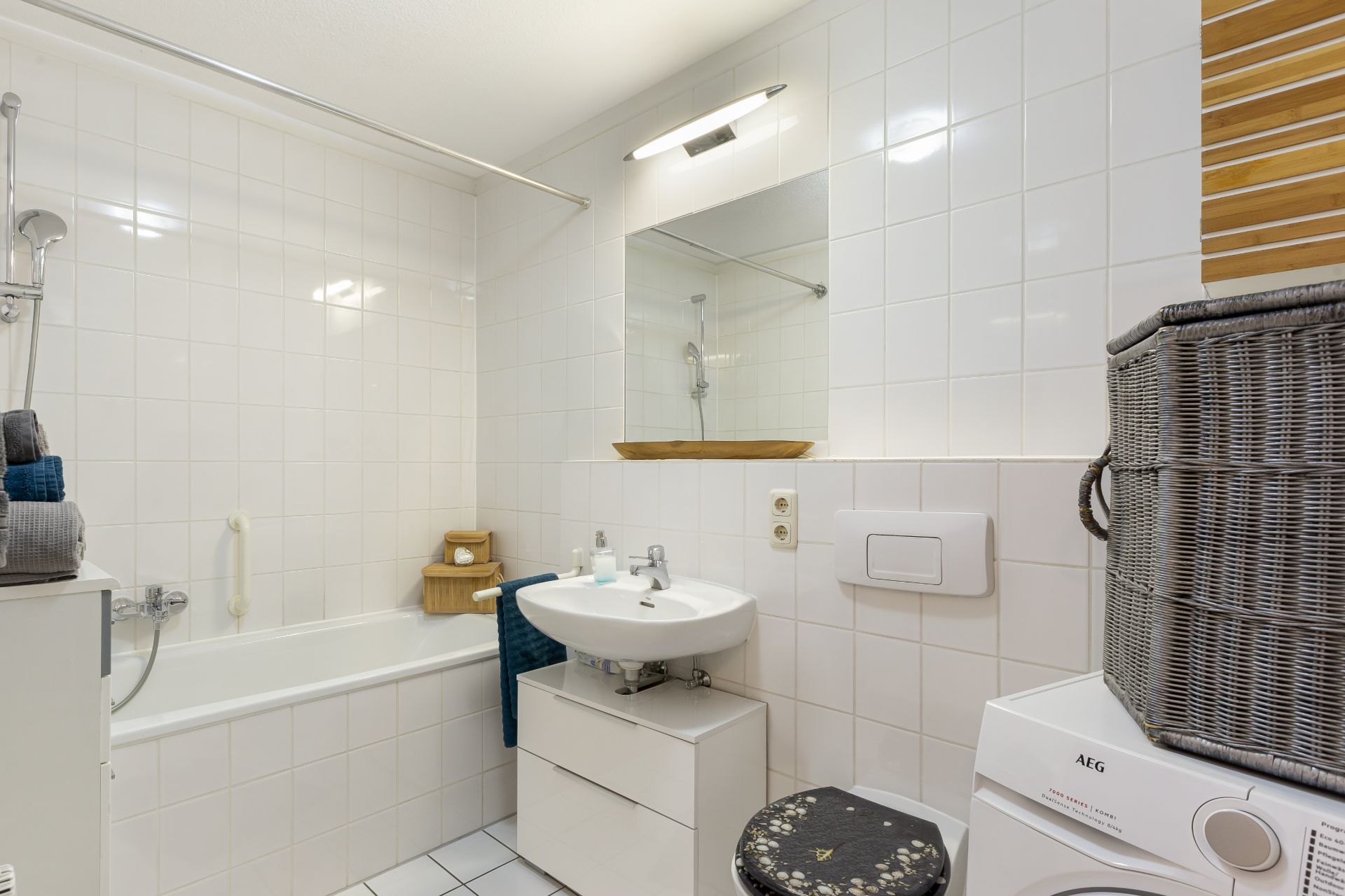 Helles Badezimmer mit Badewanne, Waschbecken, Toilette und Waschmaschine.
