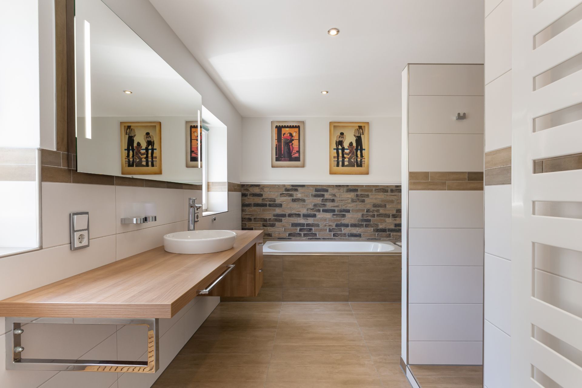 Modernes Badezimmer mit großem Spiegel, Waschbecken, Badewanne und Gemälden an der Wand.
