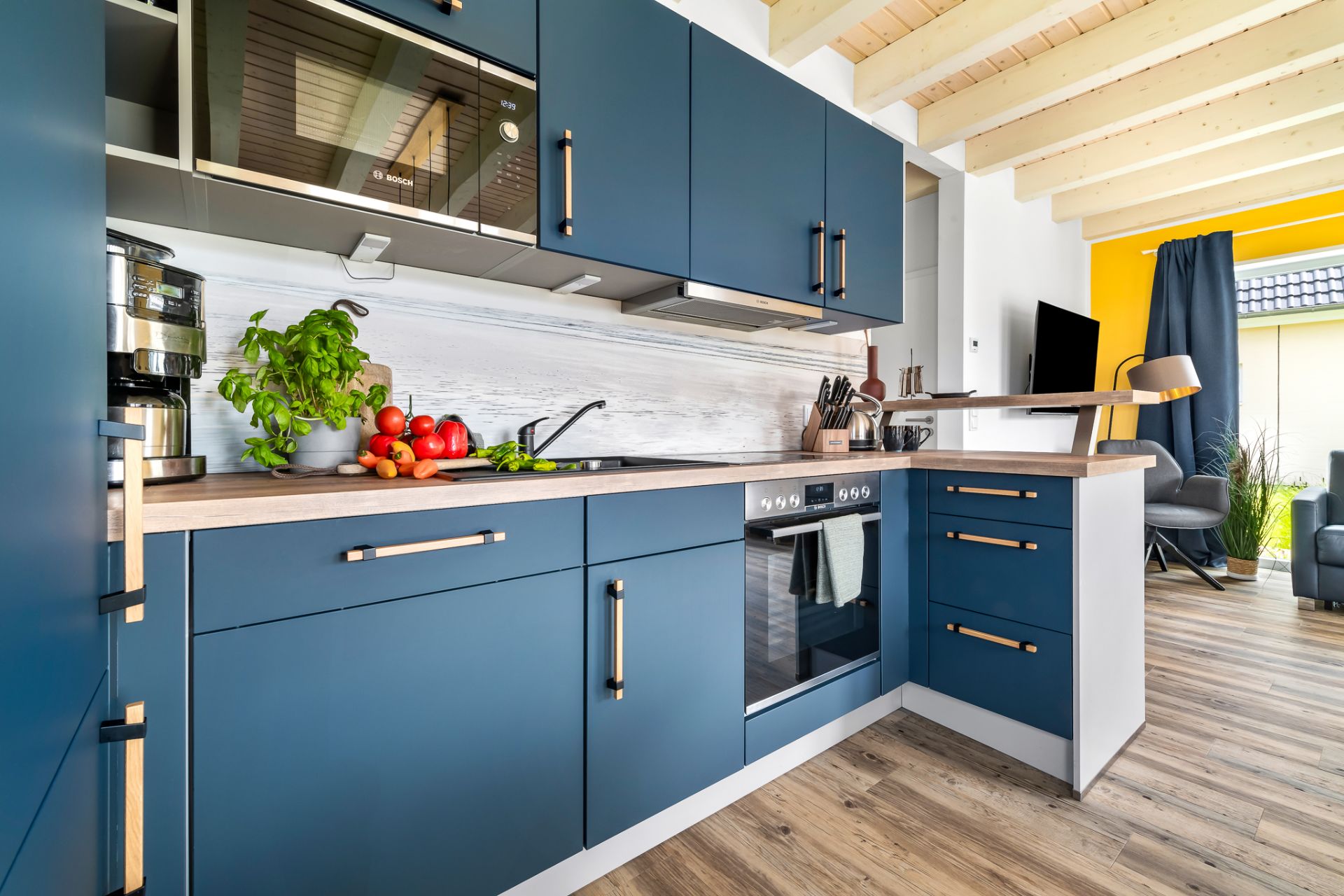 Moderne Küche mit blauen Schränken, Holzarbeitsplatte und Küchenutensilien auf der Theke.