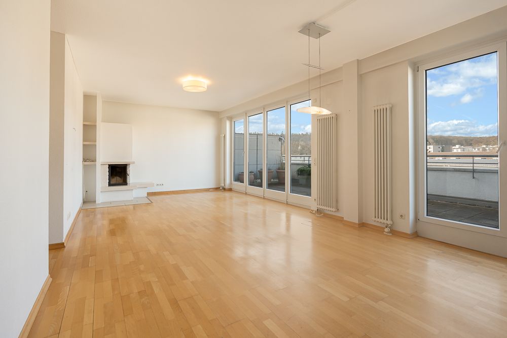 Helles Wohnzimmer mit Holzfußboden, Kamin und großen Fenstern zu einer Terrasse.