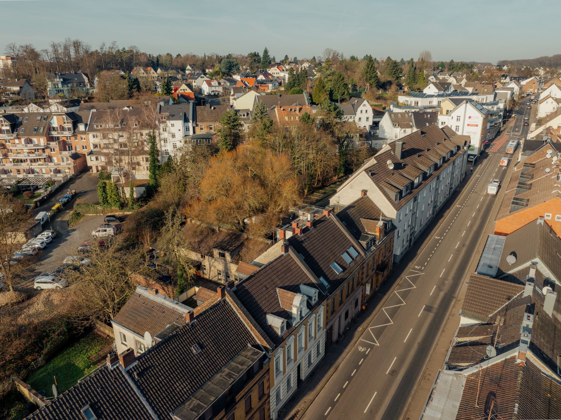 Luftaufnahme einer Wohnstraße mit Reihenhäusern und Bäumen.