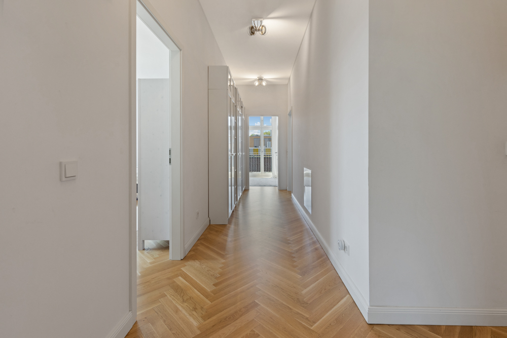 Heller Flur mit Parkettboden und Glastüren am Ende, seitlich zwei Türen.