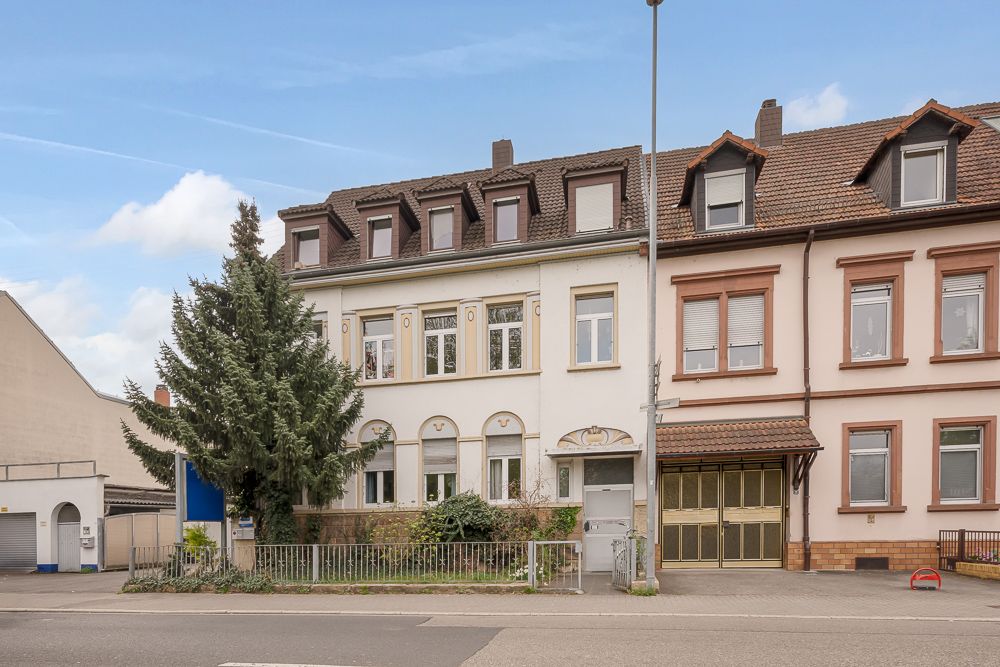 Wohnhaus mit drei Etagen, Vorgarten und großem Nadelbaum vor dem Eingang.