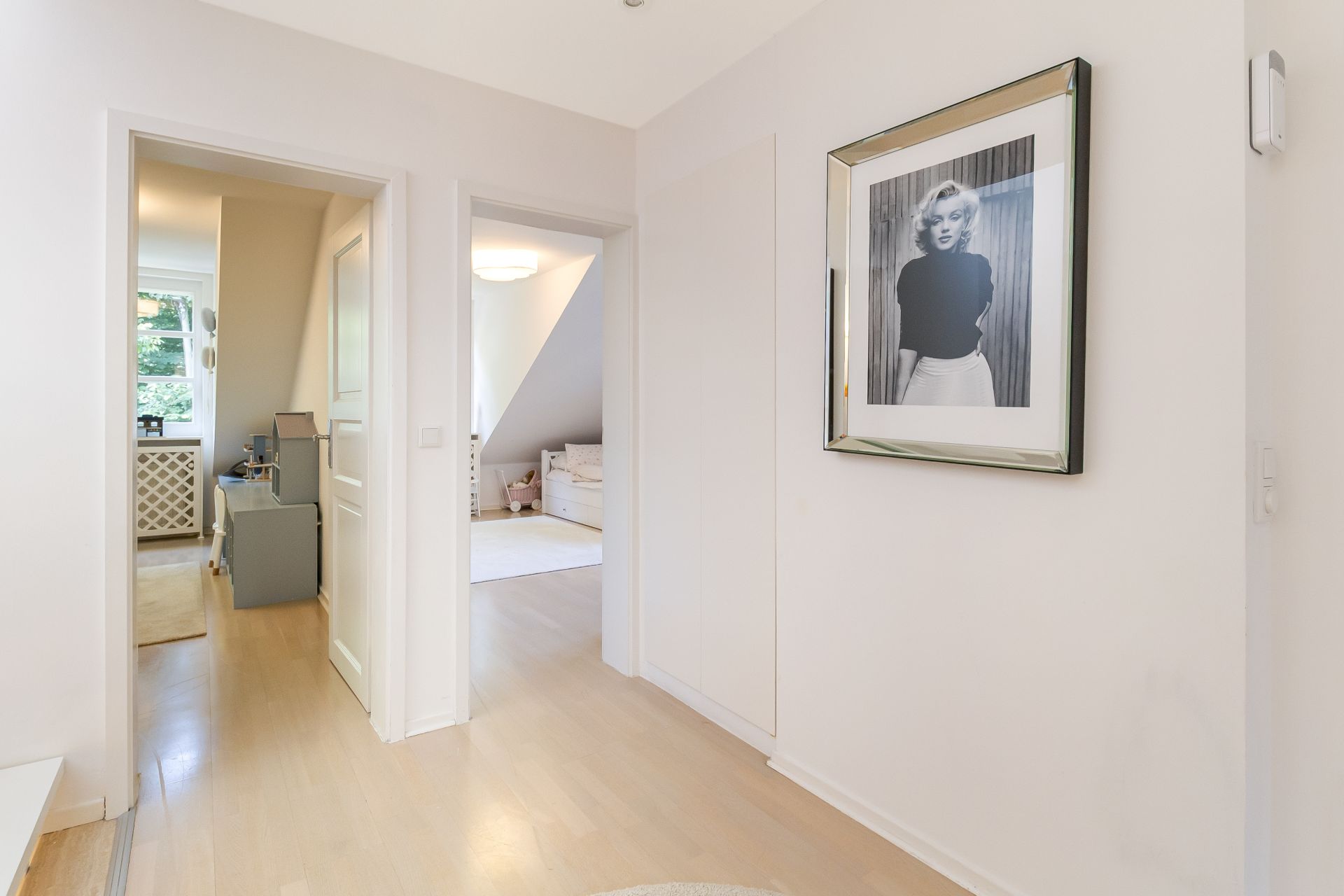 Heller Flur mit zwei offenen Türen und großem gerahmten Schwarzweiß-Foto an der Wand.