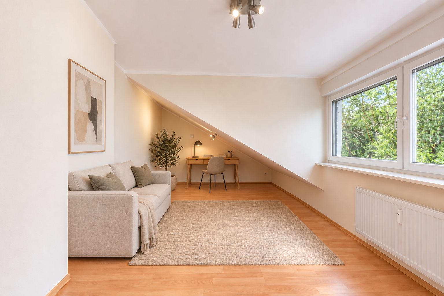 Helles Zimmer mit Sofa, Teppich, Schreibtisch unter Dachschräge und großem Fenster.
