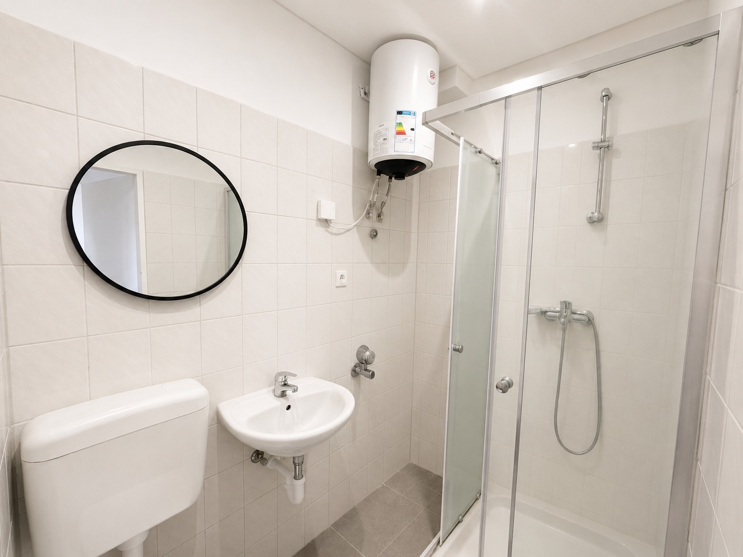 Modernes Badezimmer mit Dusche, Waschbecken, Spiegel und Wandboiler.