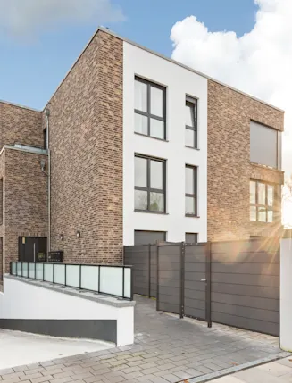 Modernes Wohngebäude aus Klinkerstein mit großen Fenstern und Tiefgarageneinfahrt.