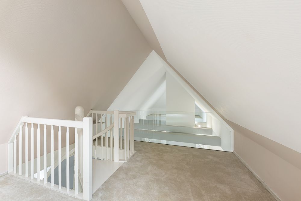 Heller Dachbodenraum mit Teppichboden und weißem Geländer an der Treppe.
