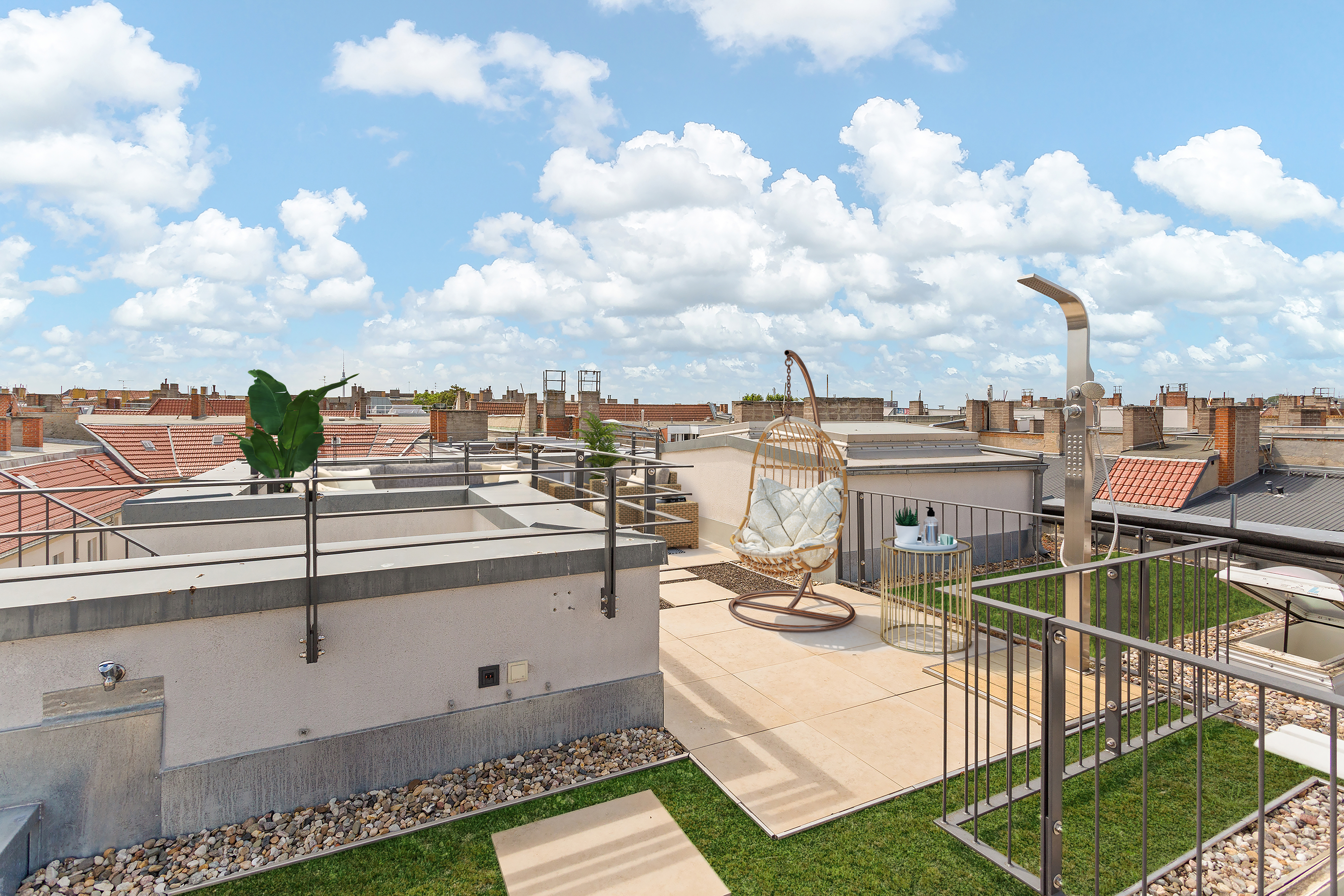 Dachterrasse mit Hängesessel, Dusche, kleinem Tisch und Blick auf benachbarte Dächer.