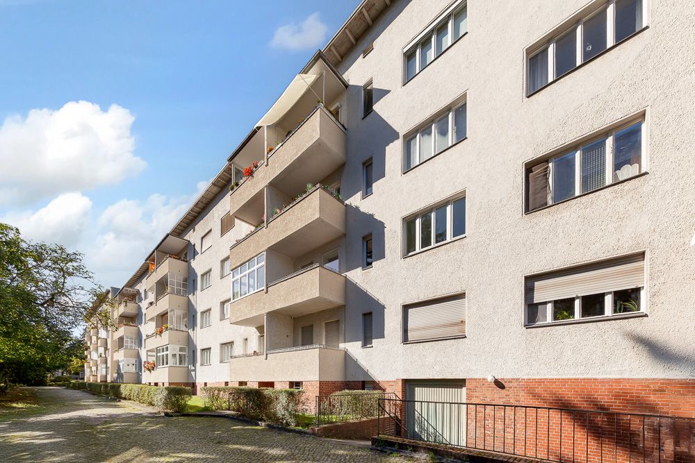 Mehrstöckiges Wohnhaus mit Balkonen und vielen Fenstern an einer ruhigen Straße.