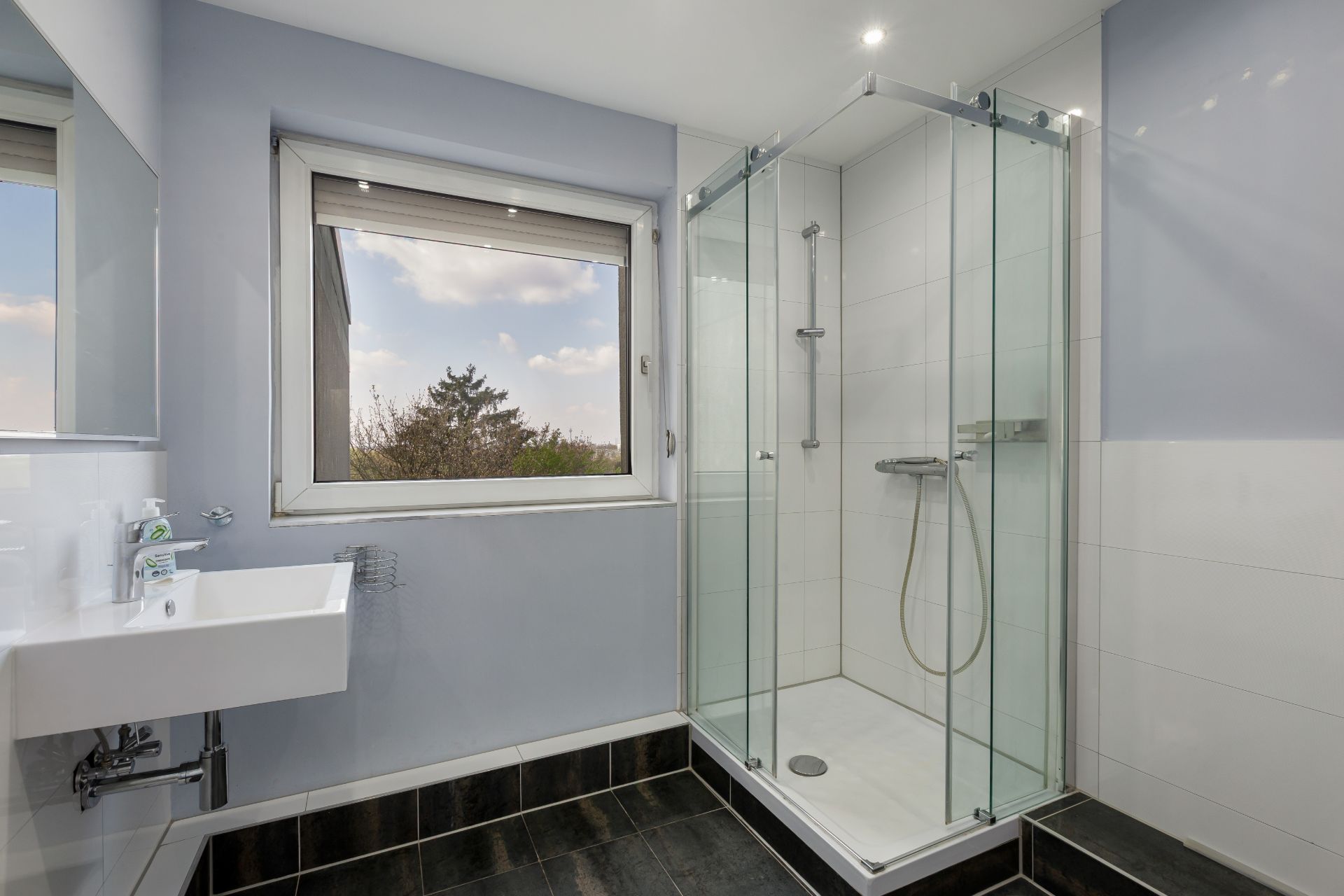 Modernes Badezimmer mit Dusche, großem Fenster und Waschbecken.