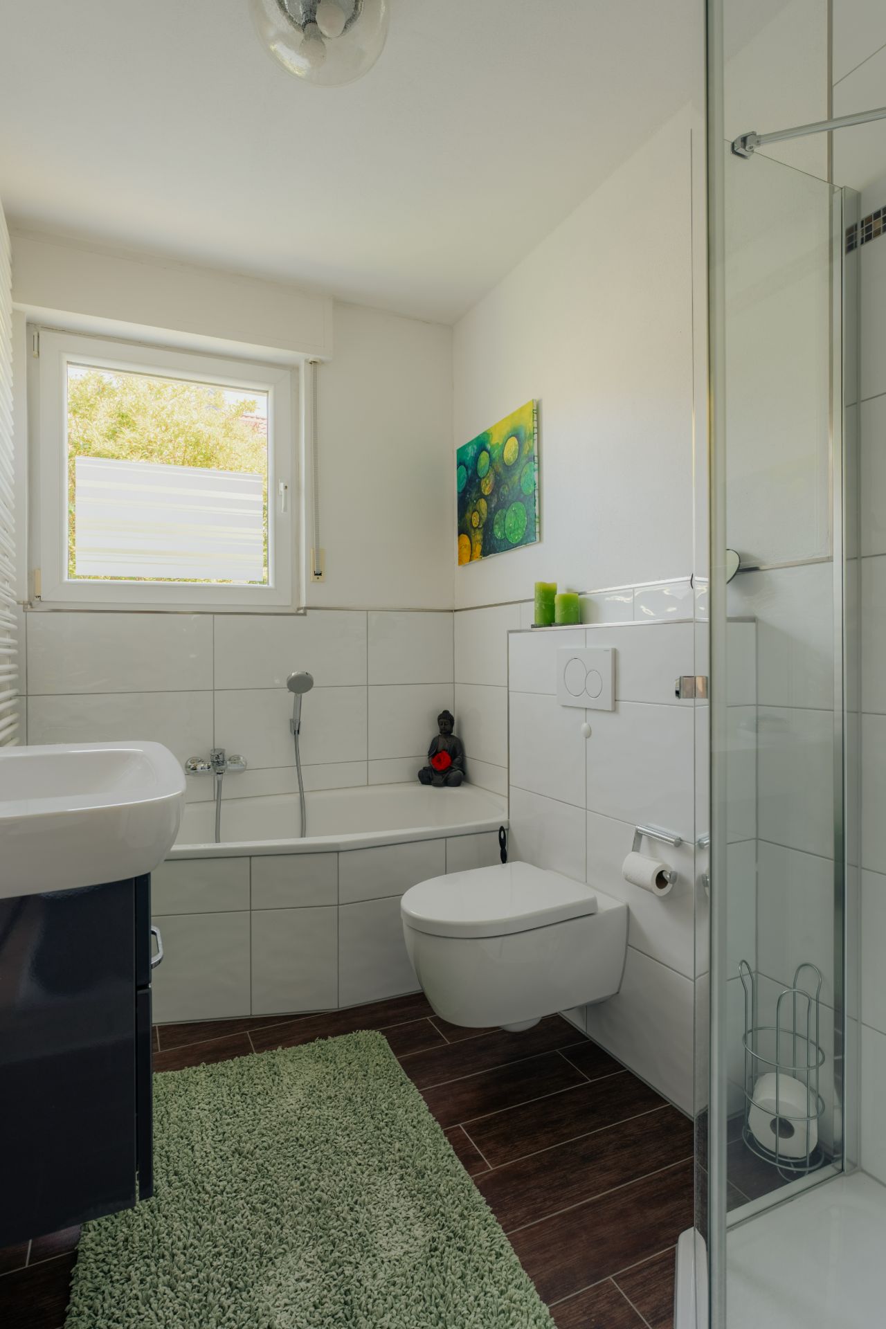 Helles Badezimmer mit Badewanne, Dusche, WC, Waschbecken und Fenster.