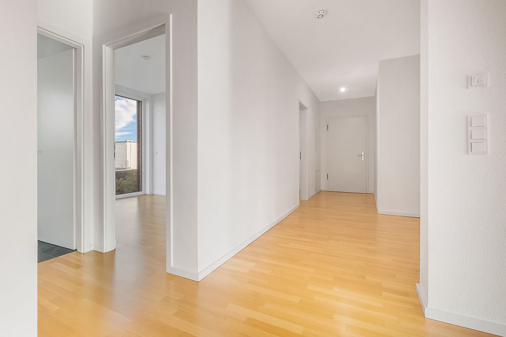 Heller Flur mit Holzboden, mehreren Türen und weißen Wänden in einer Wohnung.