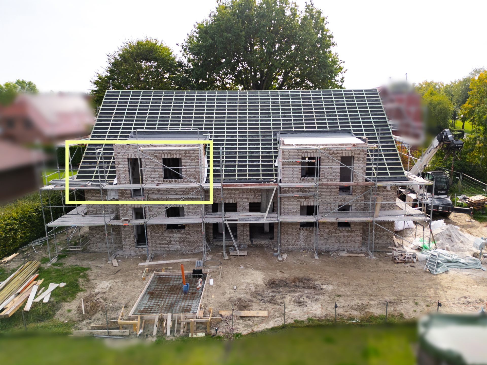 Rohbau eines zweistöckigen Wohnhauses mit Gerüst und unfertigem Dach.