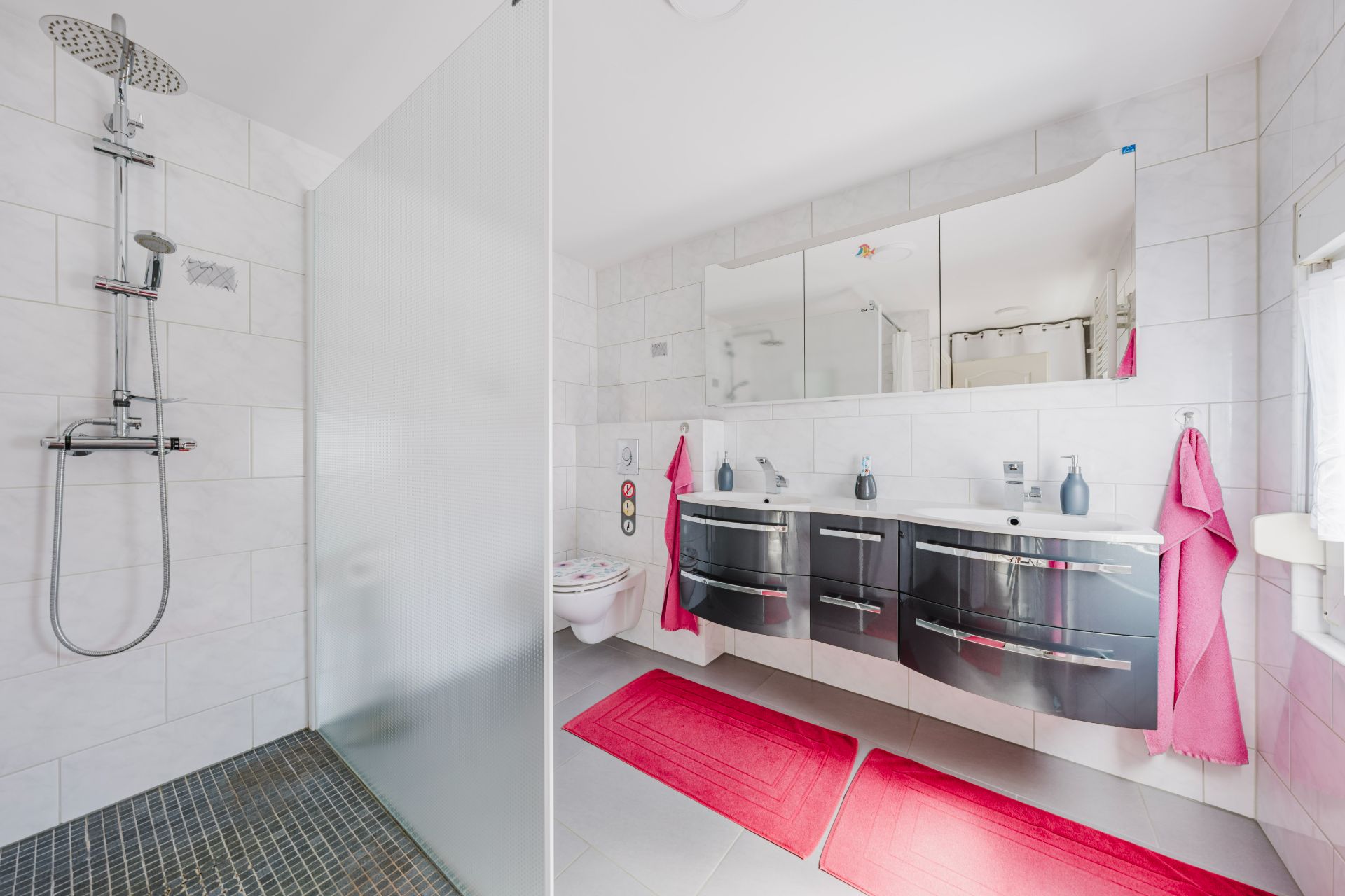 Modernes Bad mit bodengleicher Dusche, Doppelwaschbecken und roten Teppichen.