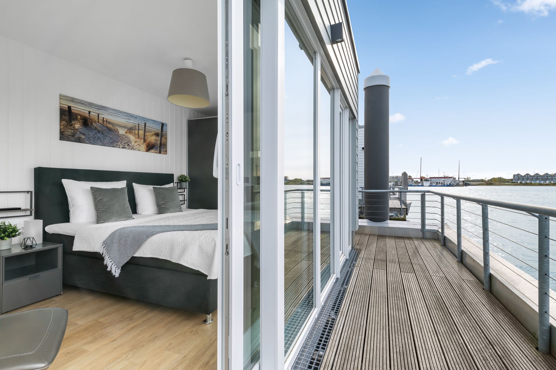 Modernes Schlafzimmer mit Doppelbett und Zugang zu einem Balkon mit Blick aufs Wasser.