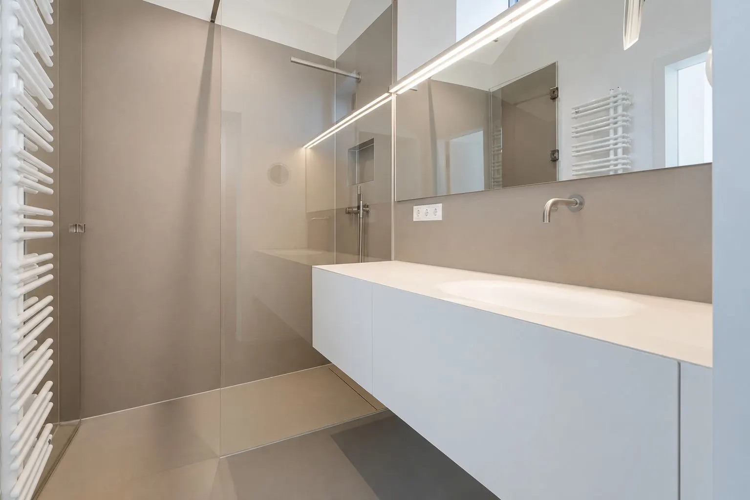 Modernes Badezimmer mit großer Dusche, weißem Waschbecken und Wandspiegel.