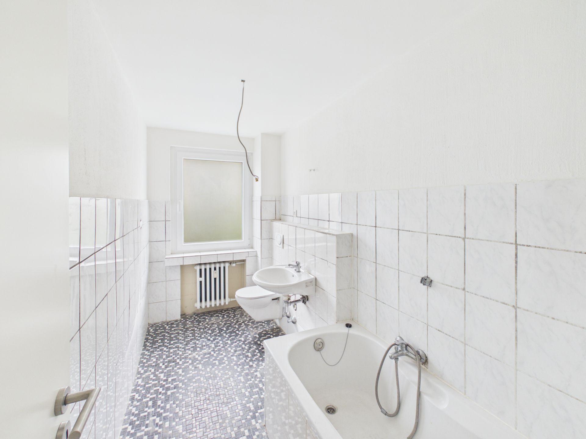 Helles Badezimmer mit Fliesen, Badewanne, zwei Waschbecken und einem Fenster im Hintergrund.