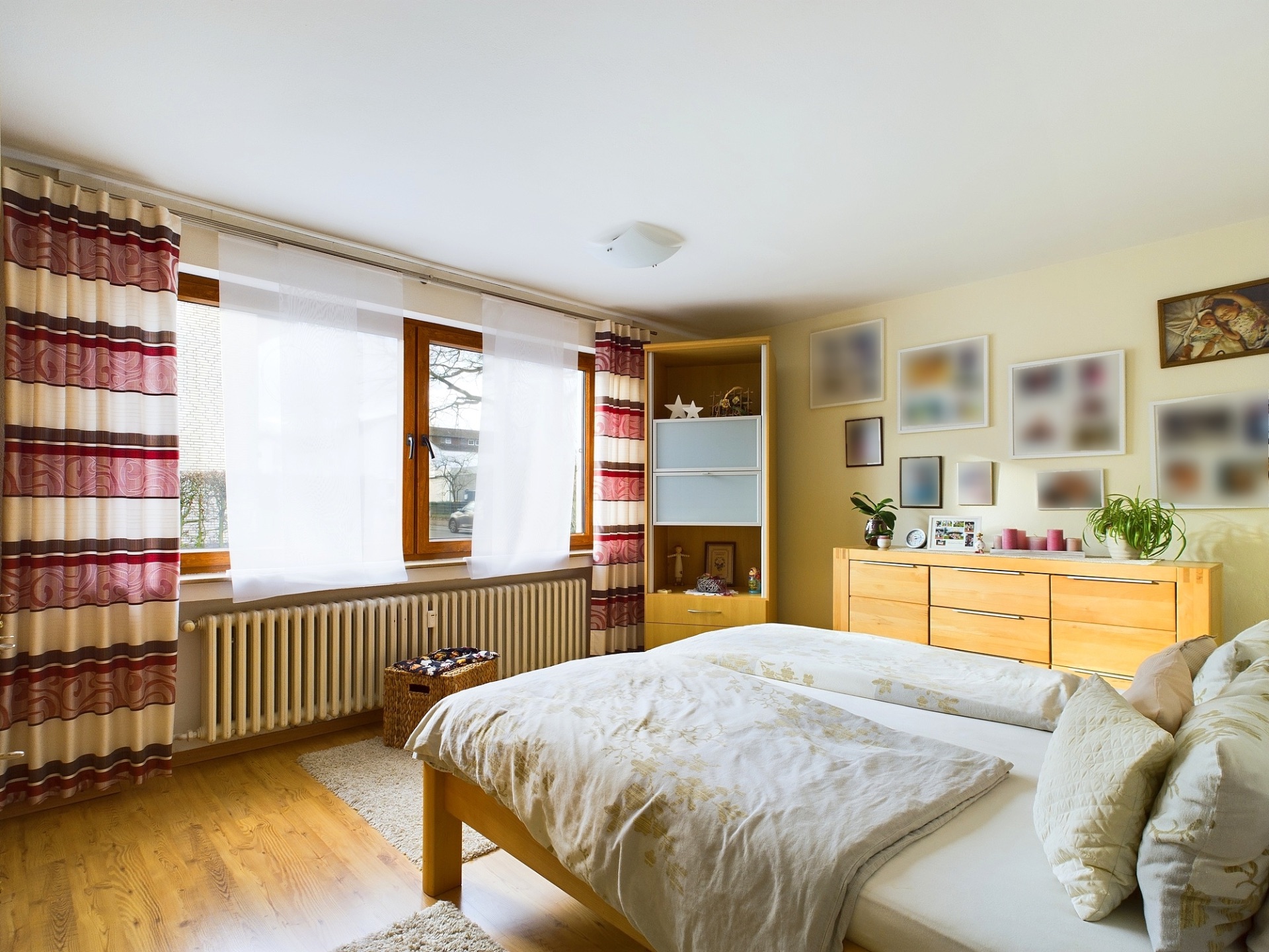 Gemütliches Schlafzimmer mit Doppelbett, hellen Vorhängen und Holzmöbeln.