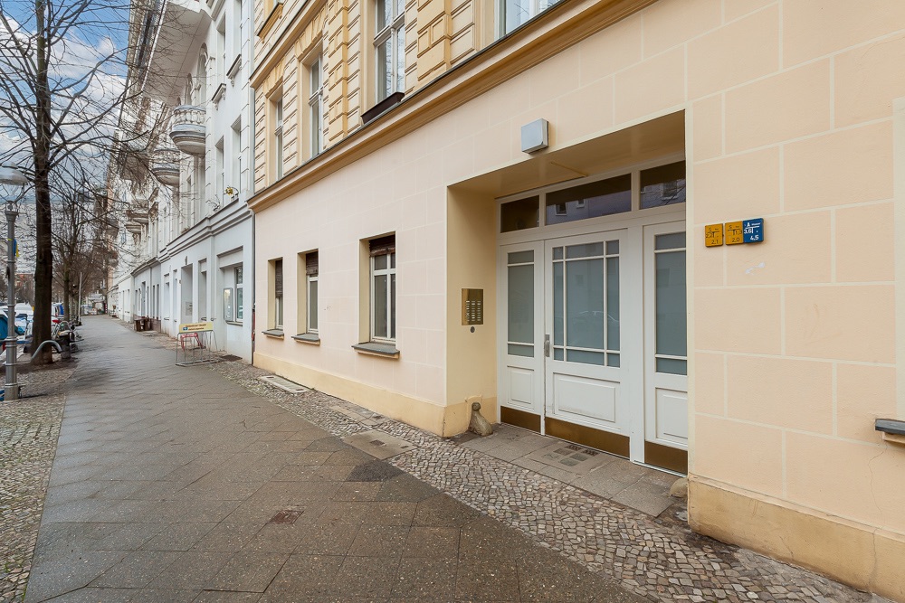 Hauseingang mit weißen Türen und Fenstern an einer ruhigen Wohnstraße.
