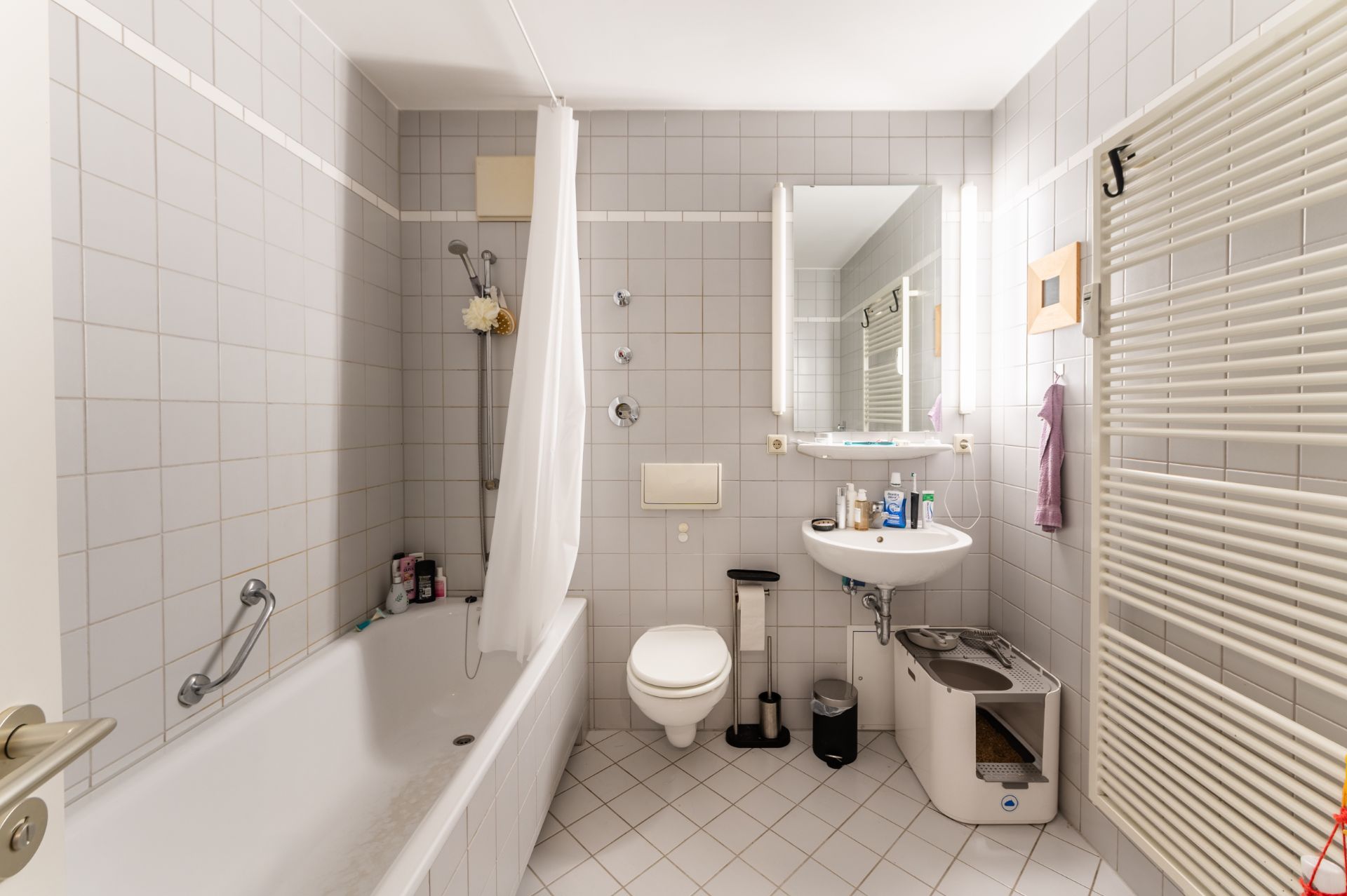 Helles Badezimmer mit Badewanne, WC, Waschbecken und beleuchtetem Spiegel.