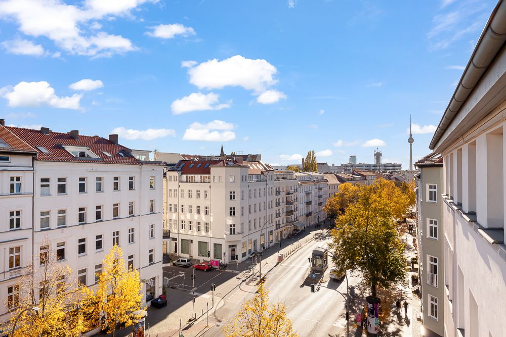 Blick auf eine sonnige städtische Straße mit Wohnhäusern und Bäumen im Herbst.