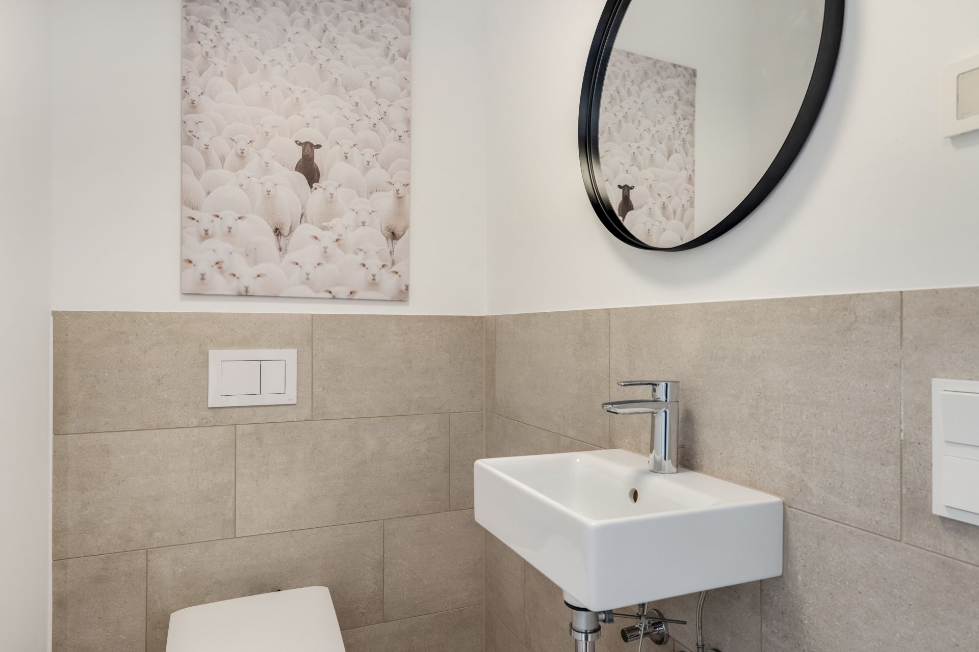 Kleines Badezimmer mit Spiegel, Waschbecken, Toilette und einem Bild an der Wand.