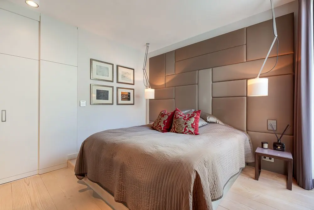 Modernes Schlafzimmer mit großem Bett, zwei Hängelampen und vier Bildern an der Wand.