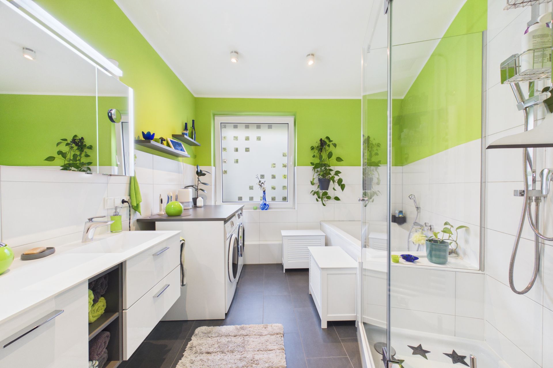 Modernes Badezimmer mit grünen Wänden, Dusche, Badewanne, Waschmaschine und Fenster.