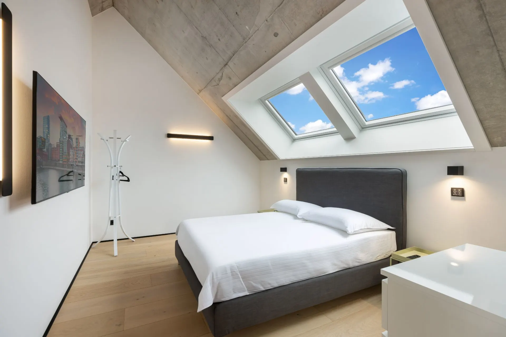 Modernes Schlafzimmer mit Doppelbett, Dachfenster und Holzfußboden.