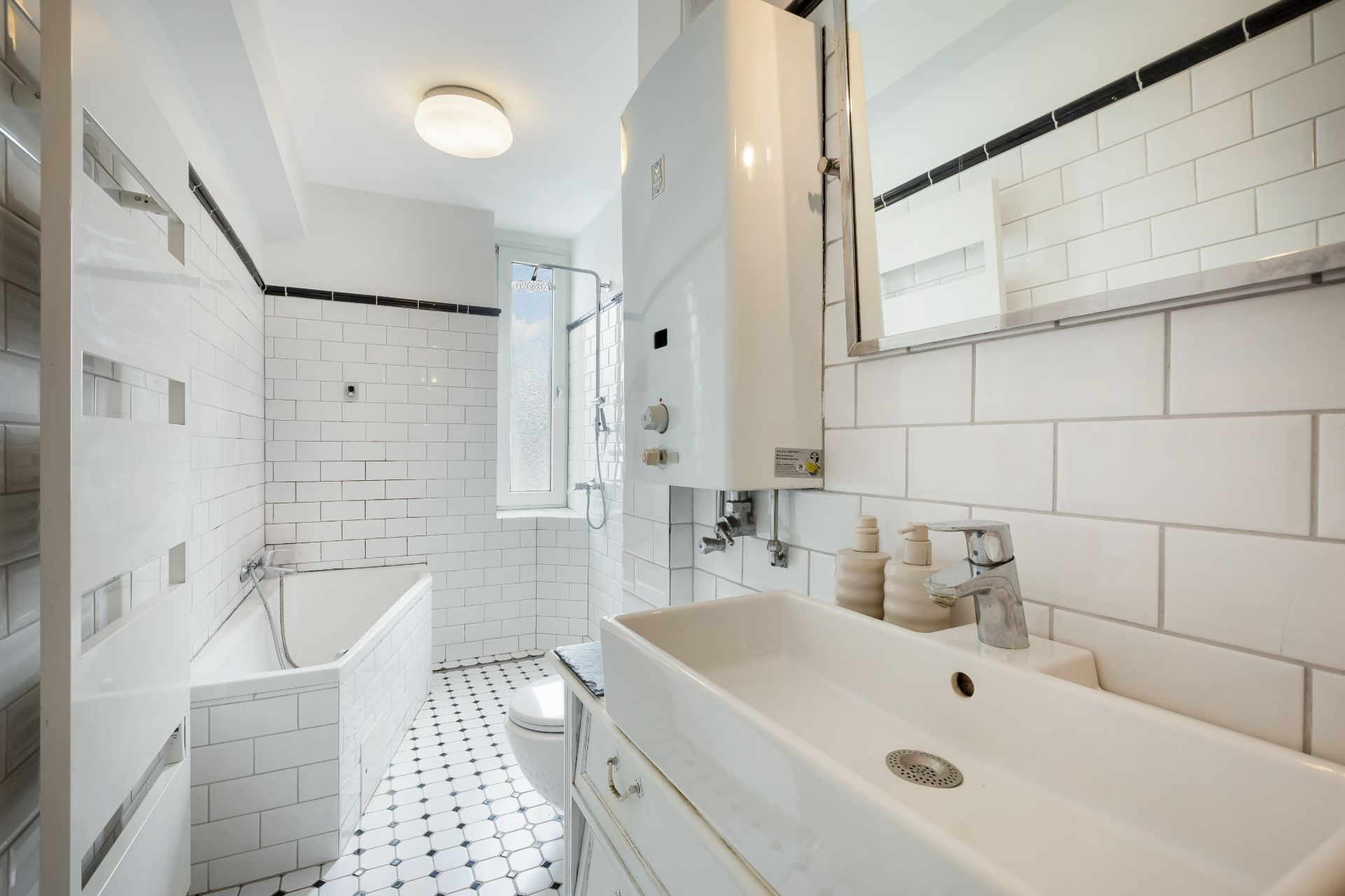 Helles Badezimmer mit Badewanne, Waschbecken, Toilette und weiß gefliesten Wänden.