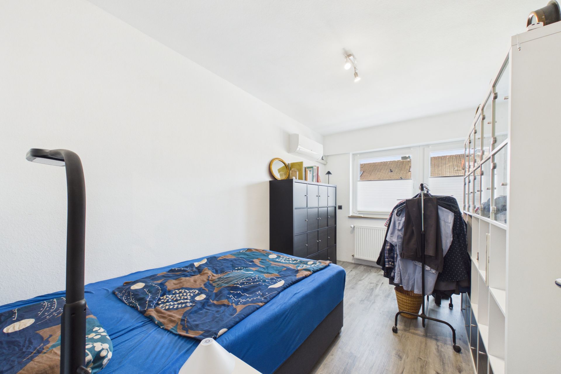 Schlafzimmer mit Einzelbett, Schrank, Regal und Fenster mit Tageslicht.