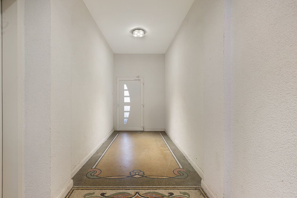 Schlichter Flur mit verziertem Boden und weißer Tür am Ende.