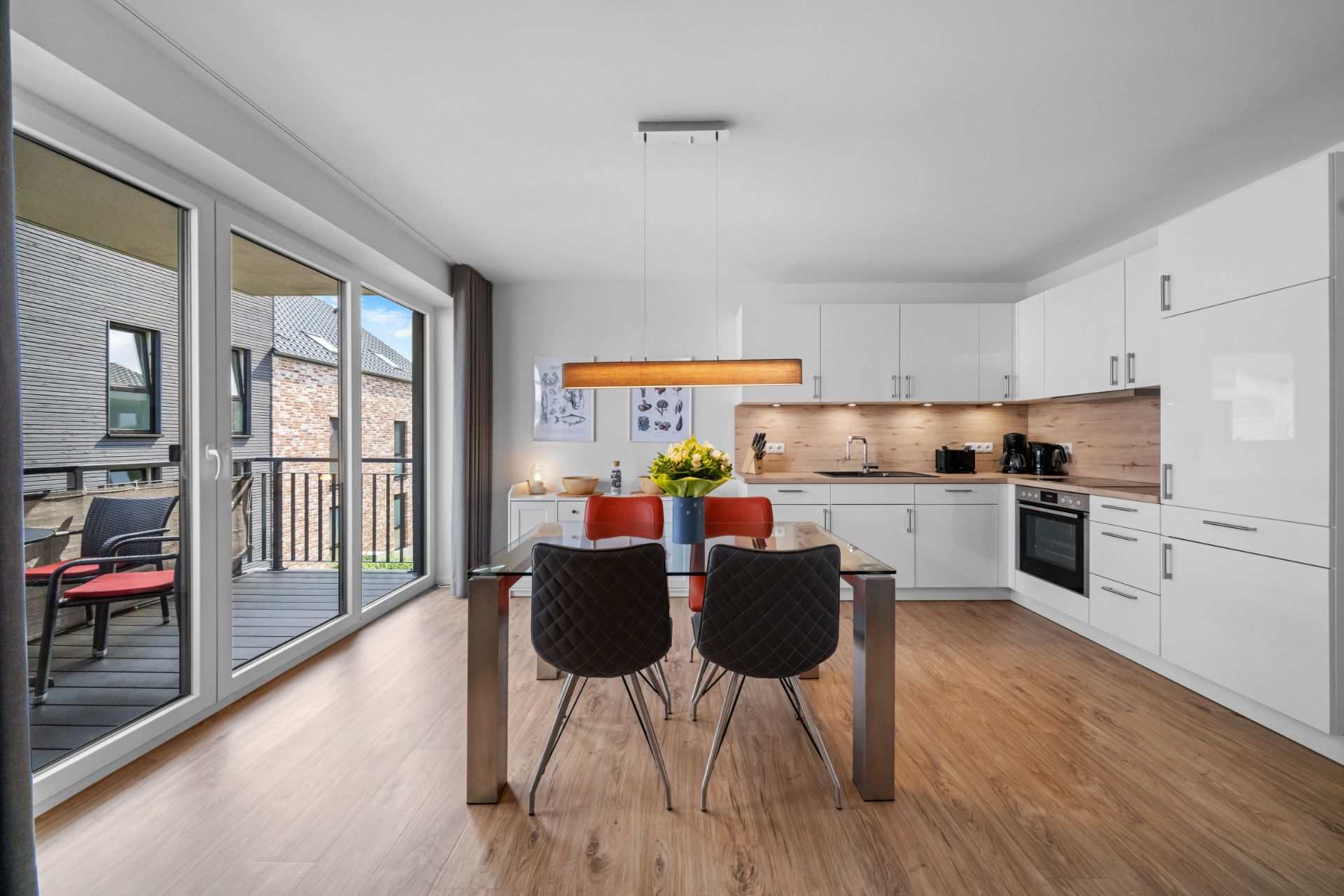 Moderne Küche mit Esstisch, vier Stühlen und Zugang zu einem Balkon.