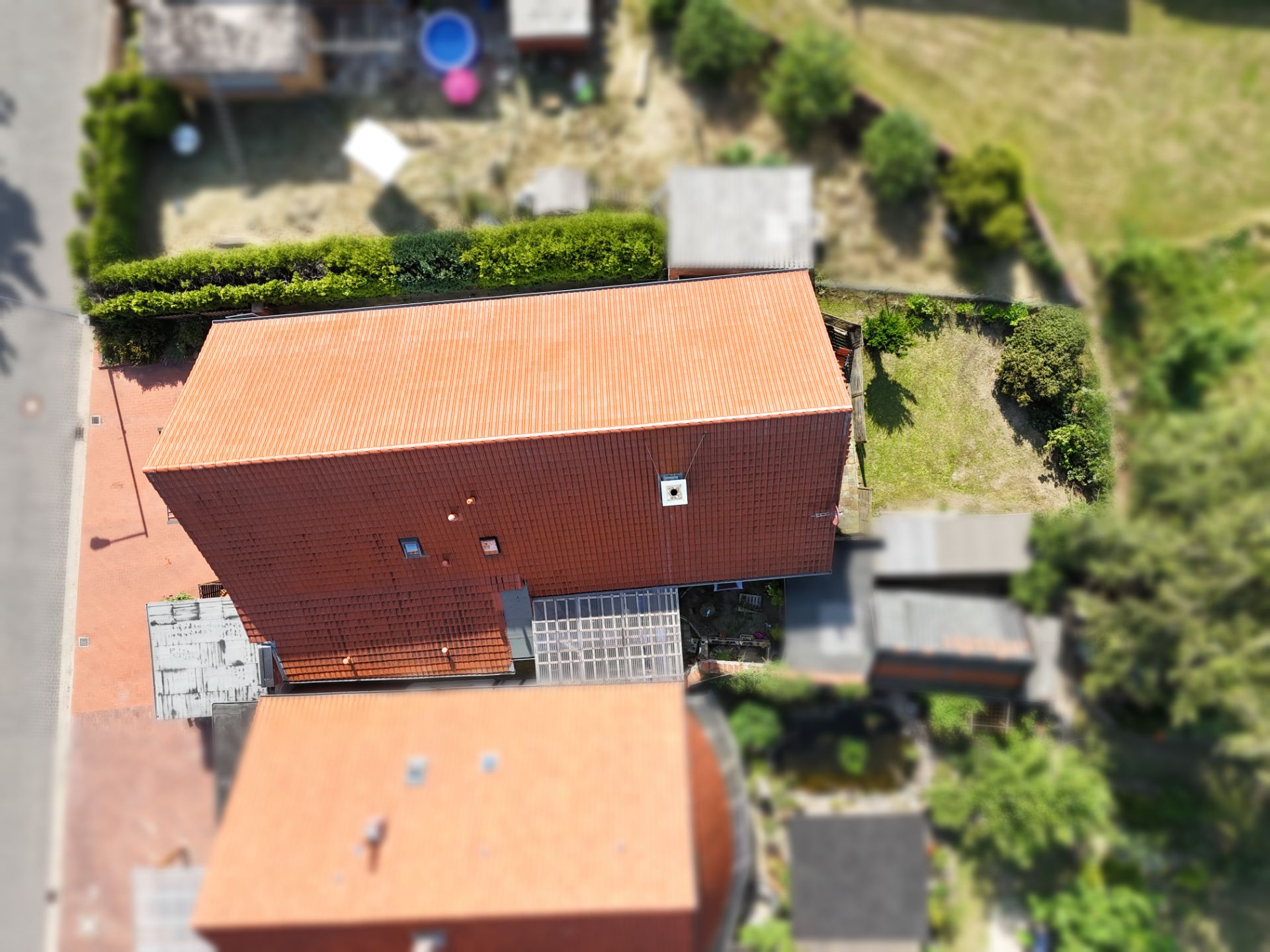 Luftaufnahme eines Hauses mit rotem Dach und kleinem Garten dahinter.